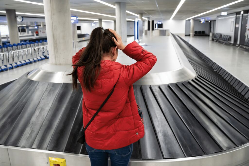 Passageira preocupada aguardando mala na esteira do aeroporto