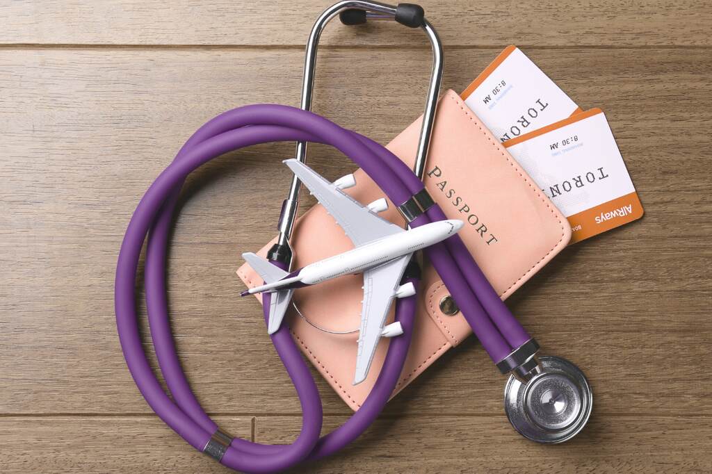 Passaporte, passagens e estetoscópio, escolha entre seguro viagem ou seguro saúde