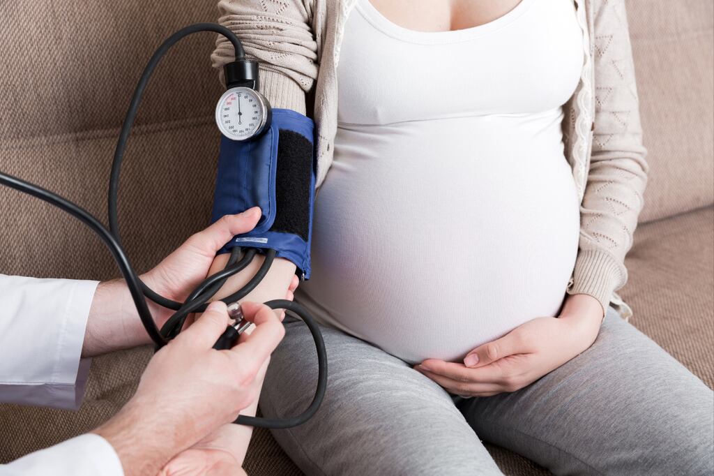Gestante em consulta médica medindo pressão reforça a importância do seguro viagem para gestantee m emergências